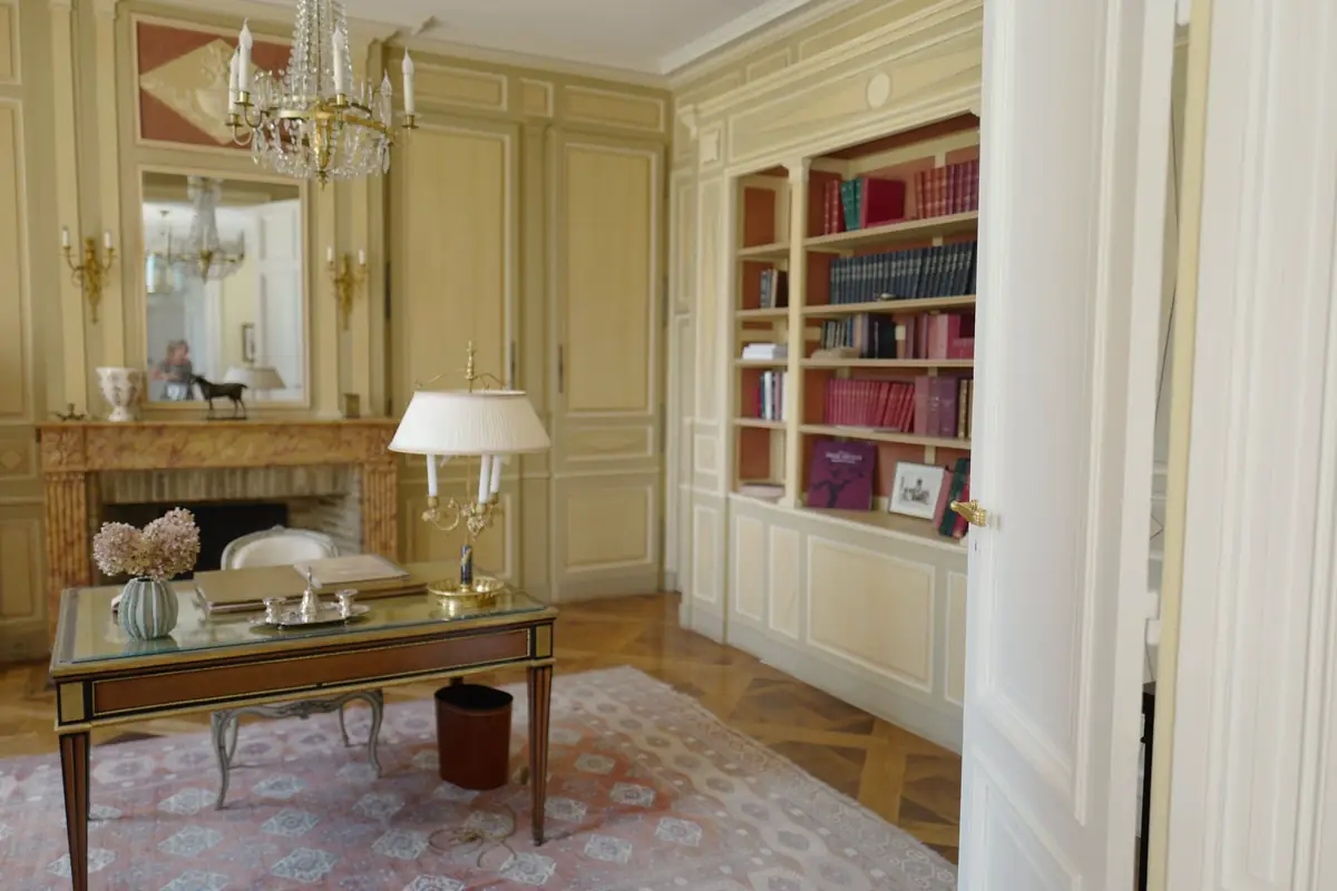 Salon à boiseries crème, cheminée et bibliothèque, parquet ancien