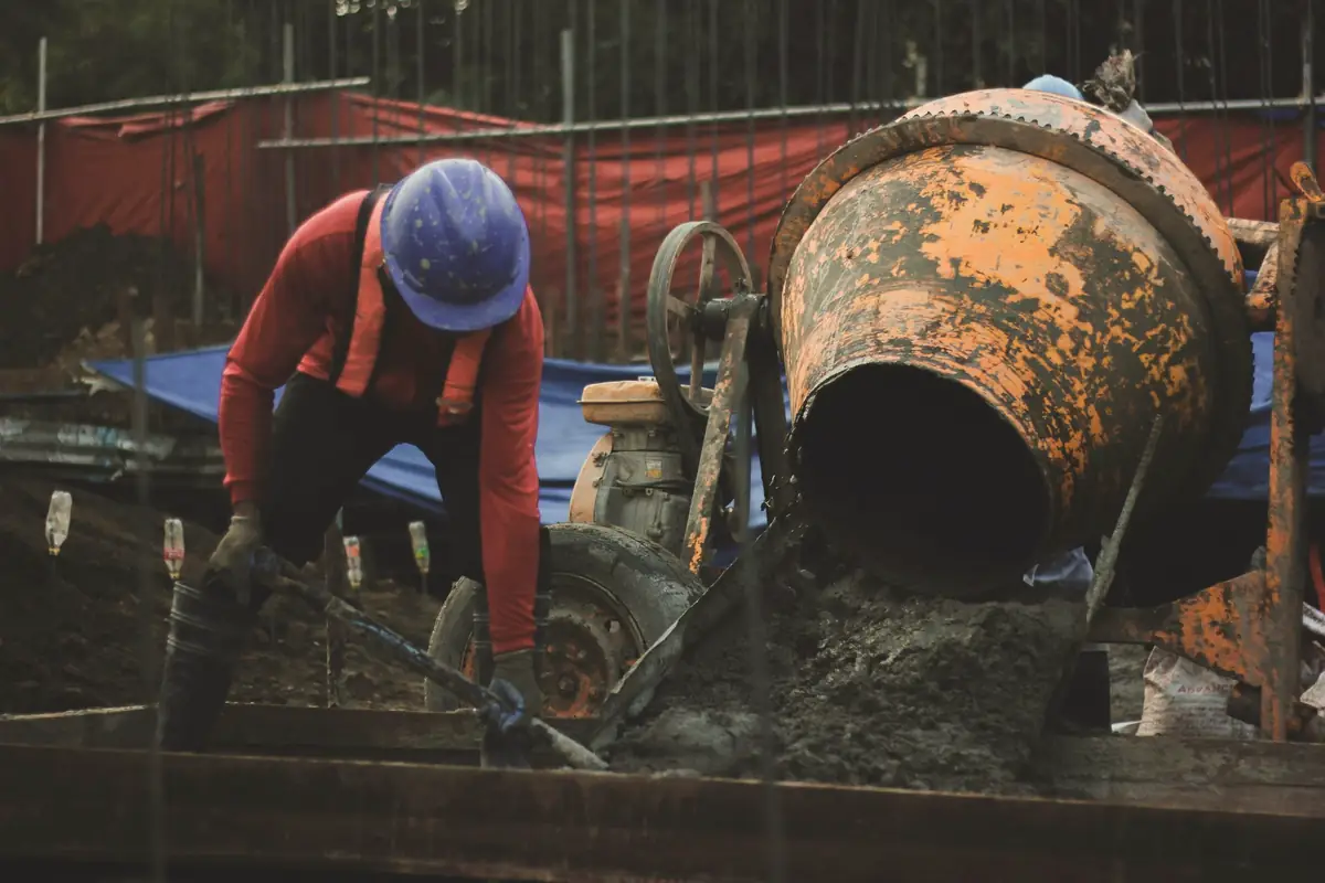 Ouvrier casqué au travail près d’une bétonnière sur un chantier